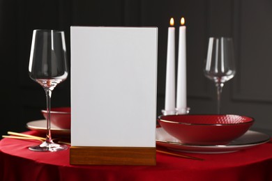 Photo of Menu holder, clean dishware and cutlery on red table in restaurant