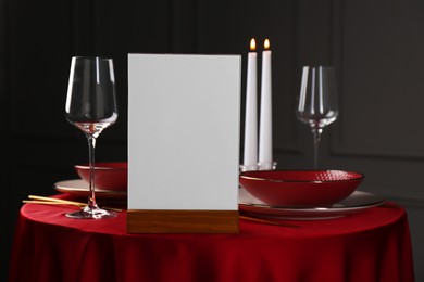 Photo of Menu holder, clean dishware and cutlery on red table in restaurant