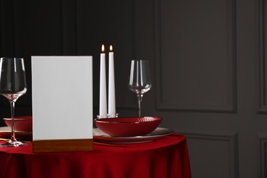 Photo of Menu holder, clean dishware and cutlery on red table in restaurant, space for text