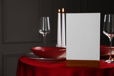 Photo of Menu holder, clean dishware and cutlery on red table in restaurant, space for text