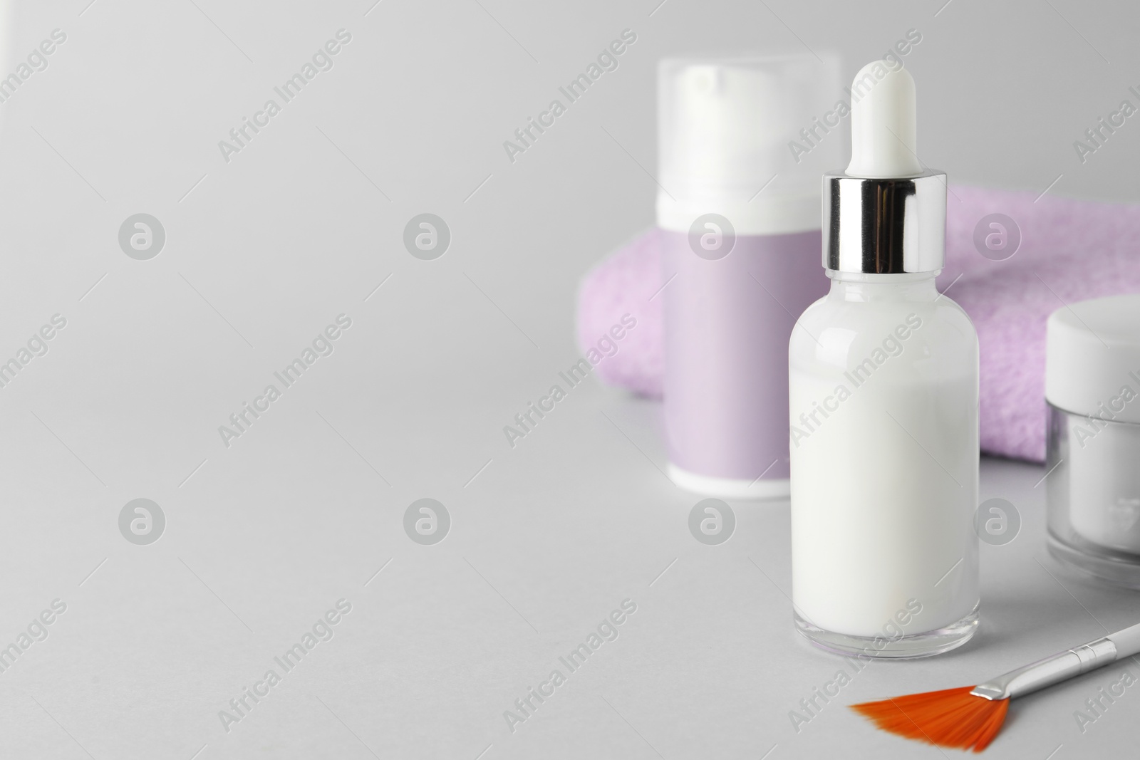 Photo of Bottle of chemical peel, cosmetic products and brush on light background, space for text. Peeling procedure