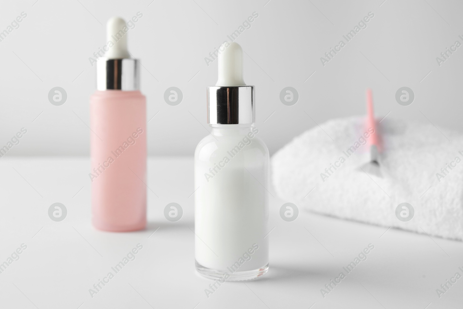 Photo of Bottles of chemical peel, towel and brush on light background, closeup. Peeling procedure