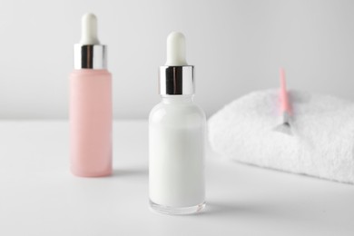 Photo of Bottles of chemical peel, towel and brush on light background, closeup. Peeling procedure