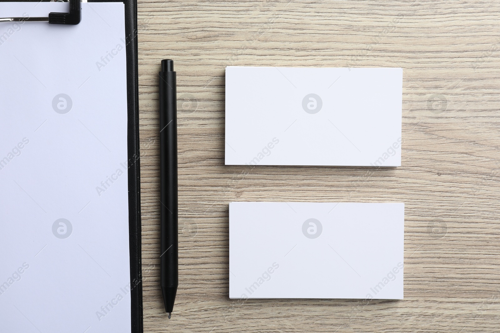 Photo of Blank business cards, clipboard with sheet and pen on wooden table, flat lay. Mockup for design