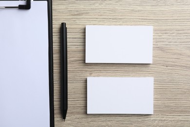 Photo of Blank business cards, clipboard with sheet and pen on wooden table, flat lay. Mockup for design