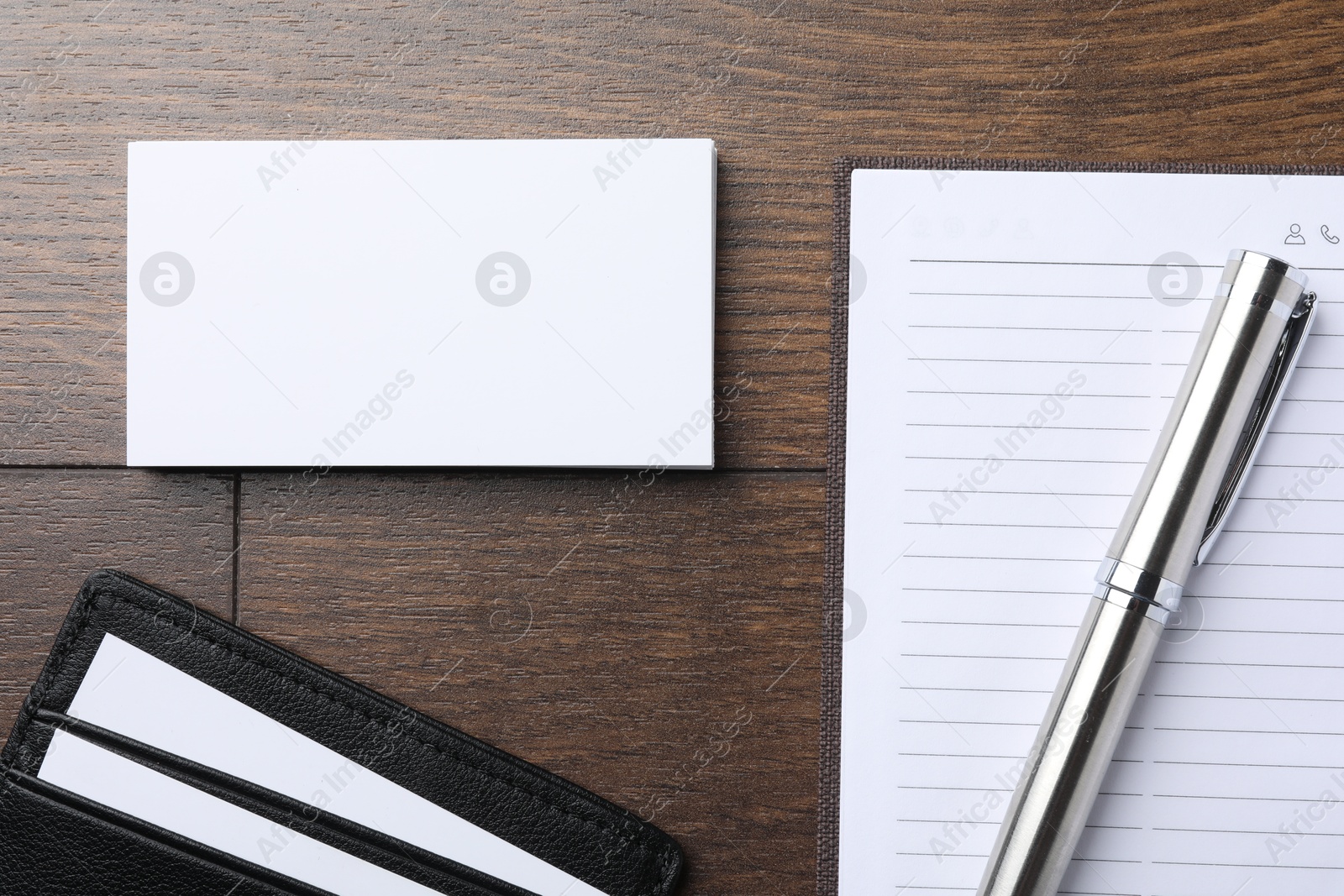 Photo of Leather card holder with blank business cards, notebook and pen on wooden table, flat lay. Mockup for design