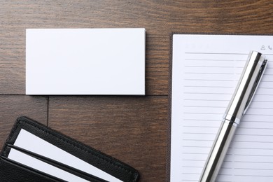 Photo of Leather card holder with blank business cards, notebook and pen on wooden table, flat lay. Mockup for design