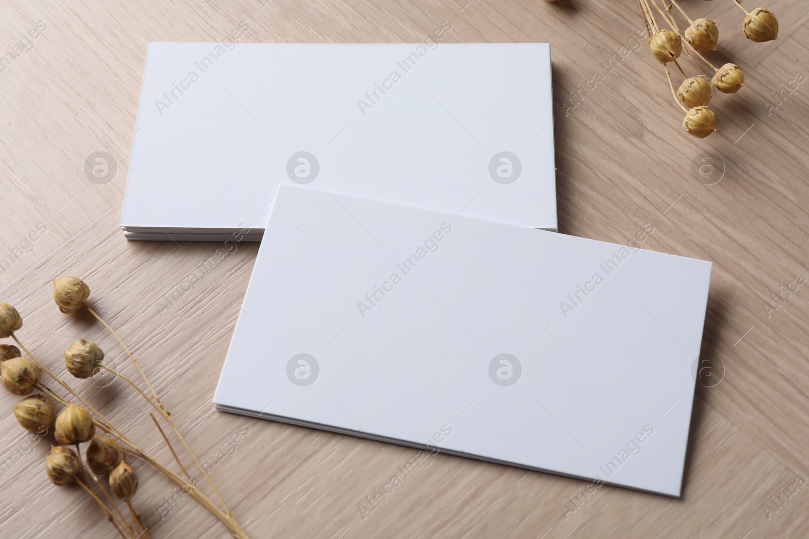 Photo of Blank business cards and dried herbs on wooden table. Mockup for design