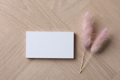 Photo of Blank business cards and dried plants on wooden table, flat lay. Mockup for design