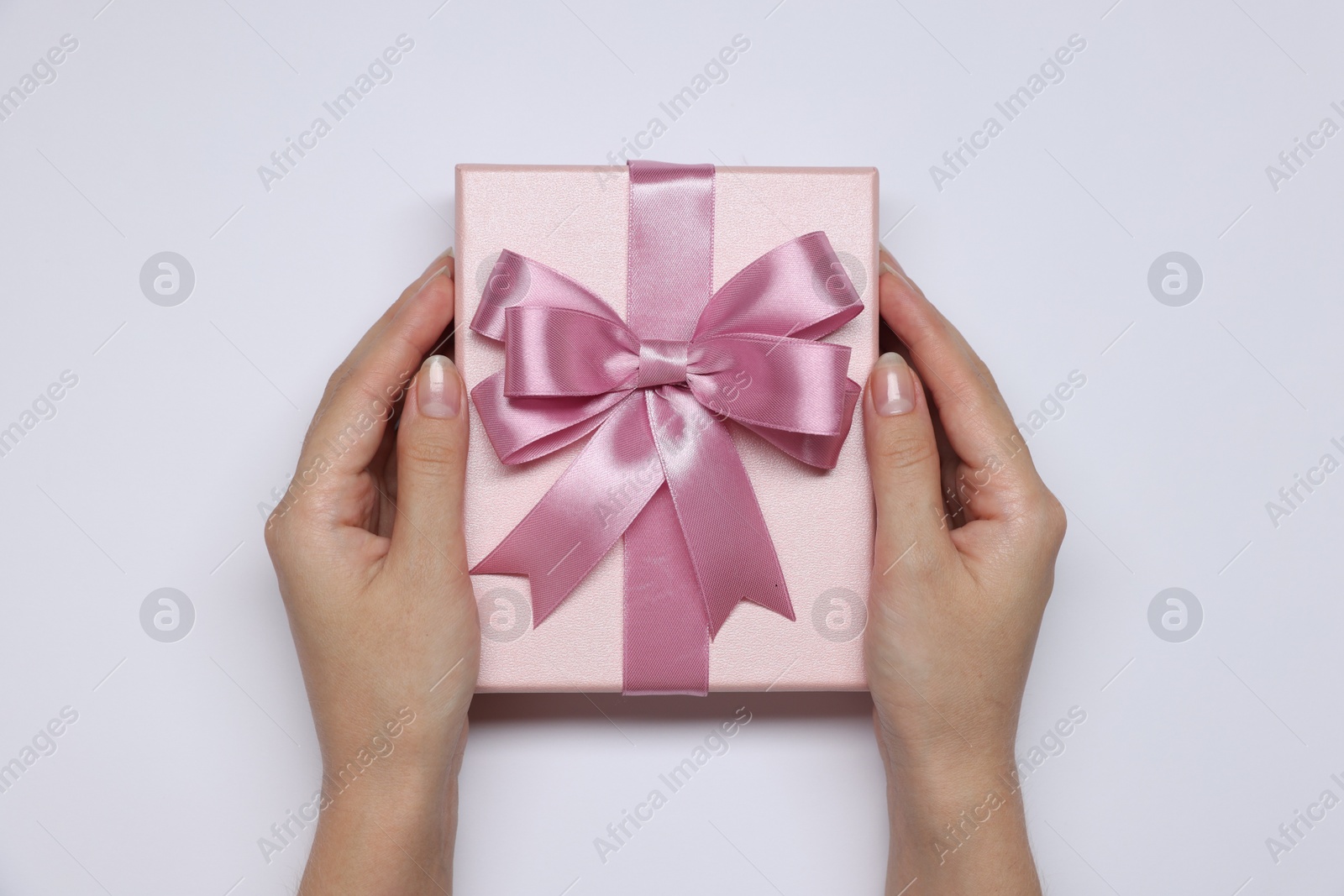 Photo of Woman holding gift box with bow on white background, top view