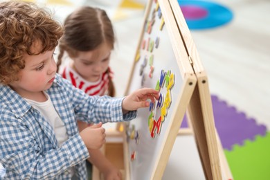 Photo of Little children learning alphabet with magnetic letters on board in kindergarten