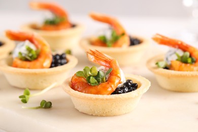 Photo of Delicious canapes with shrimps and black caviar on light table, closeup