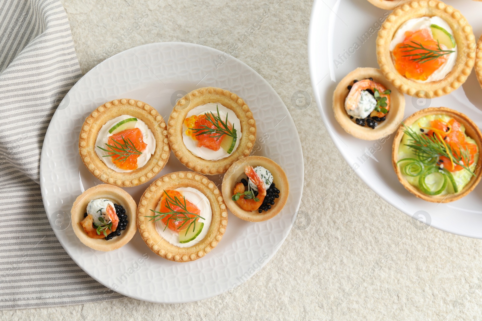 Photo of Delicious canapes with shrimps, salmon and caviar on beige textured table, flat lay