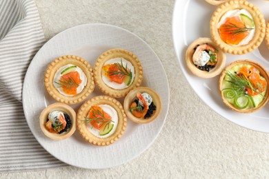 Photo of Delicious canapes with shrimps, salmon and caviar on beige textured table, flat lay