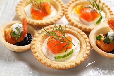 Photo of Delicious canapes with shrimps, salmon and caviar on plate, closeup