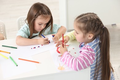 Cute little children drawing at table indoors