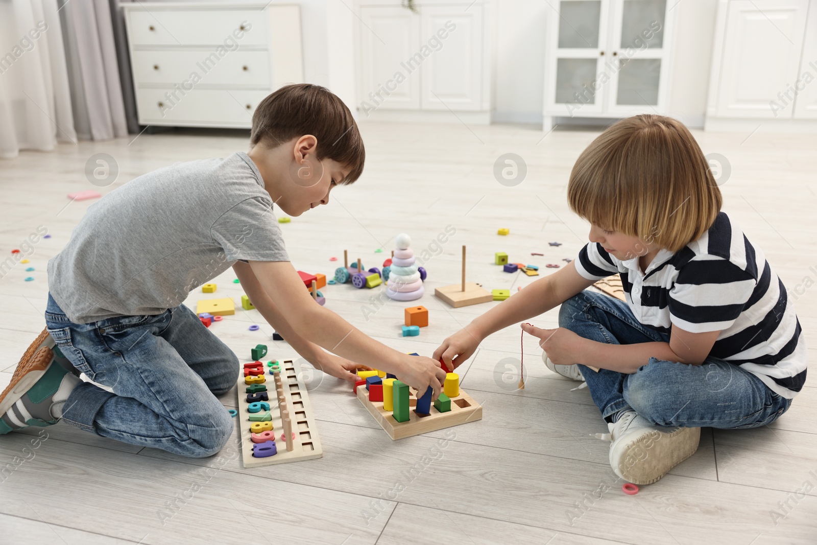 Photo of Cute little children playing with wooden blocks on floor indoors