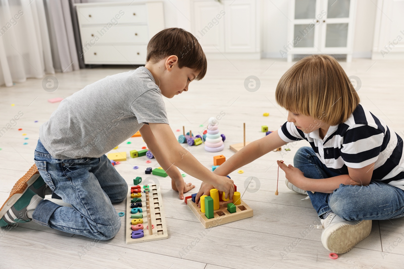 Photo of Cute little children playing with wooden blocks on floor indoors