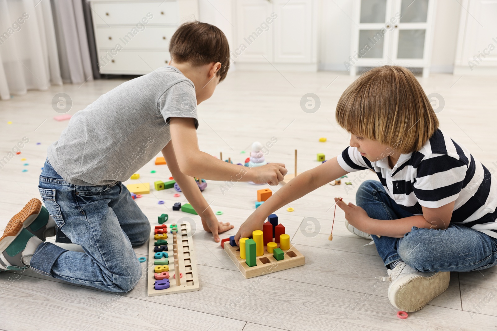 Photo of Cute little children playing with wooden blocks on floor indoors