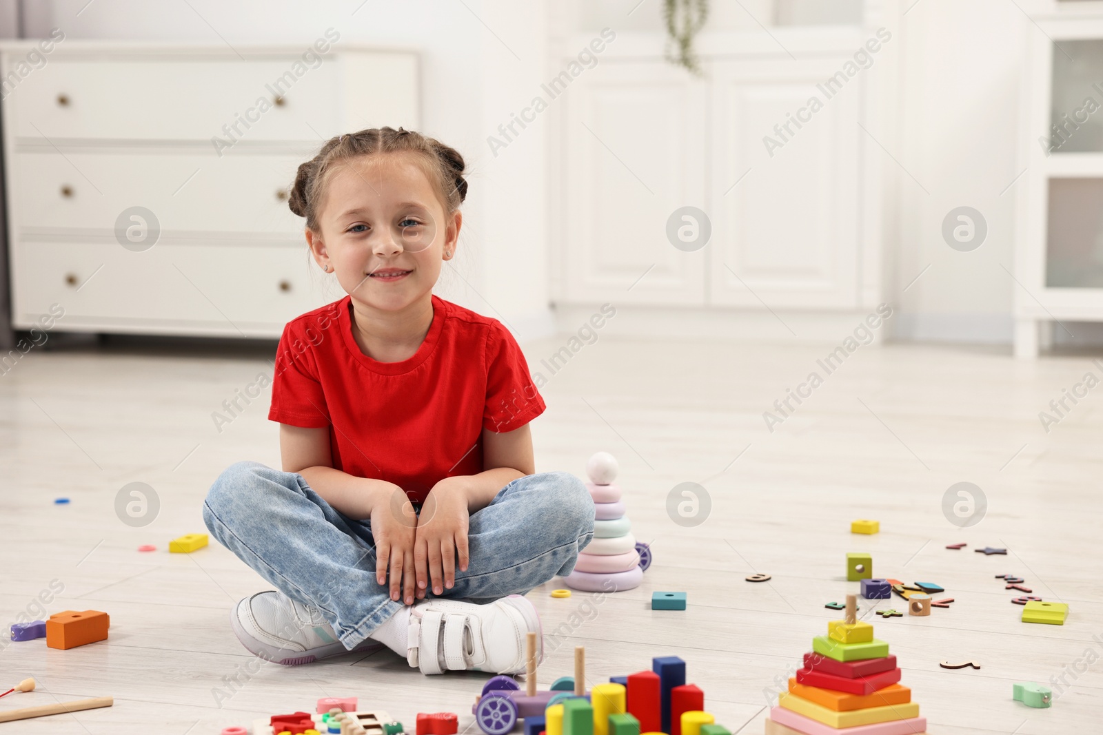 Photo of Cute little girl playing on floor indoors