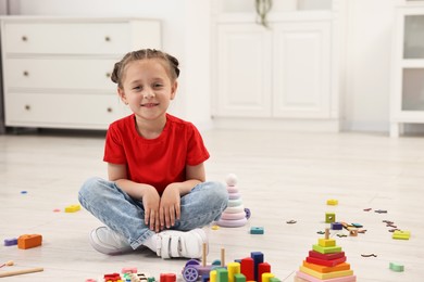 Photo of Cute little girl playing on floor indoors