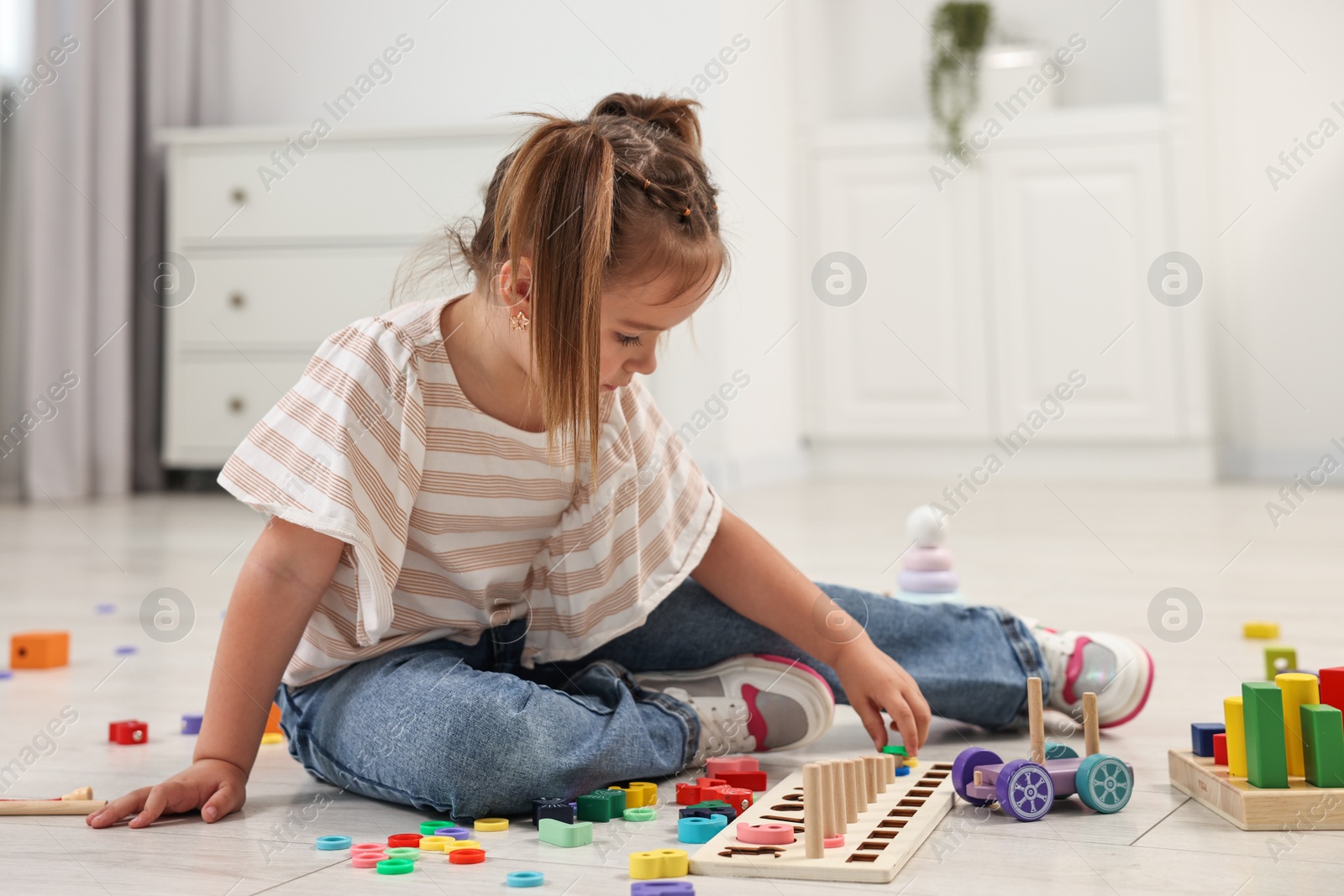 Photo of Cute little girl playing with math game Fishing for Numbers on floor indoors