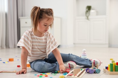 Photo of Cute little girl playing with math game Fishing for Numbers on floor indoors