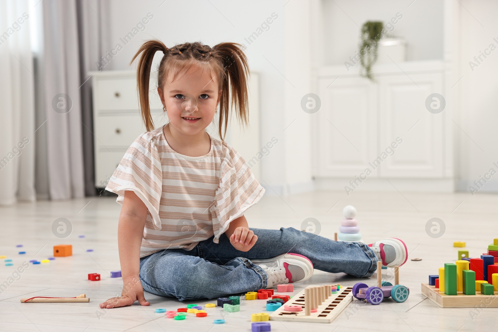 Photo of Cute little girl playing with math game Fishing for Numbers on floor indoors