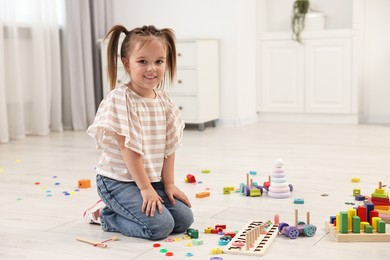 Photo of Cute little girl playing on floor indoors