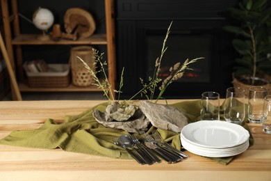 Photo of Clean dishes, stones and plants on wooden table in stylish dining room