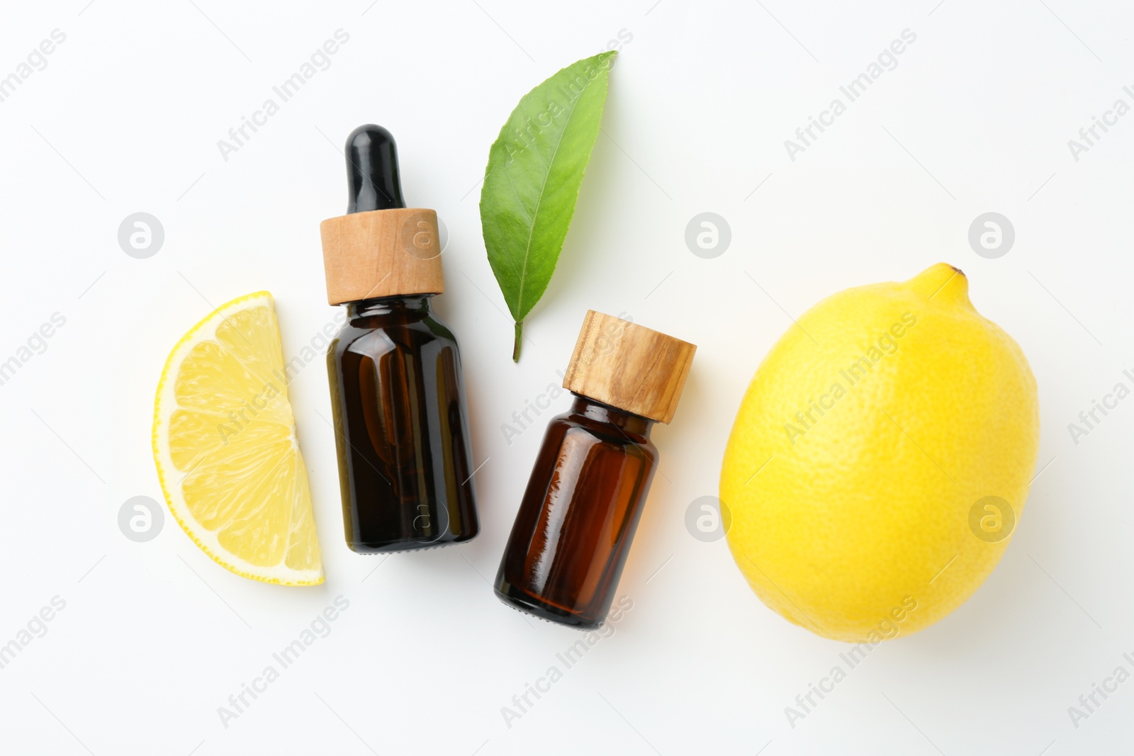 Photo of Bottles of essential oils, lemon and green leaf on white background, flat lay