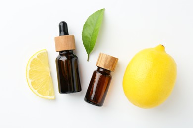 Photo of Bottles of essential oils, lemon and green leaf on white background, flat lay