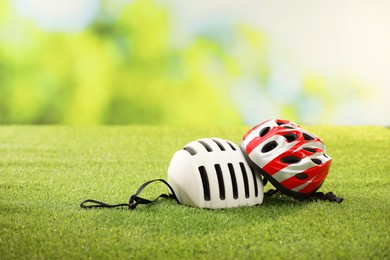 Two protective helmets on green grass, space for text