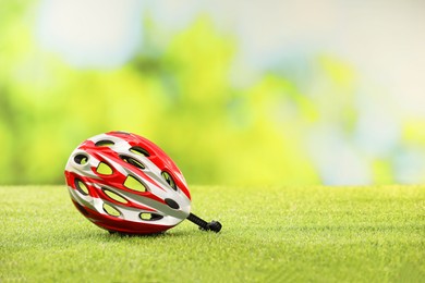 Colorful protective helmet on green grass, space for text