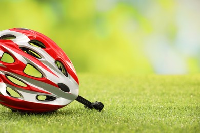 Colorful protective helmet on green grass, space for text