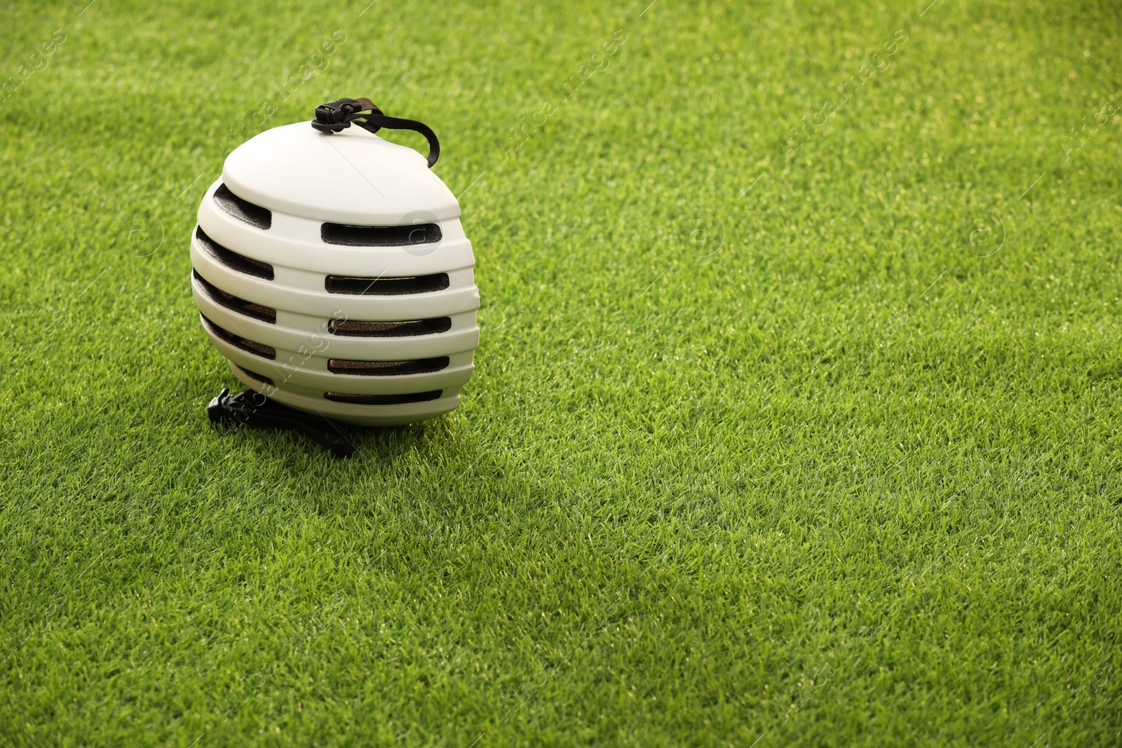 Photo of White protective helmet on green grass, space for text