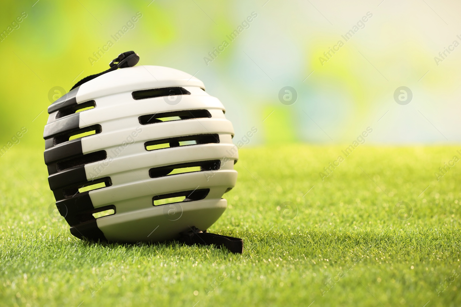 Photo of White protective helmet on green grass, space for text