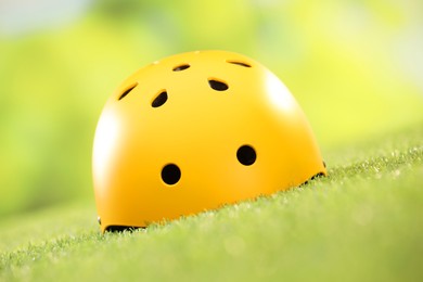 Photo of Yellow protective helmet on green grass, closeup