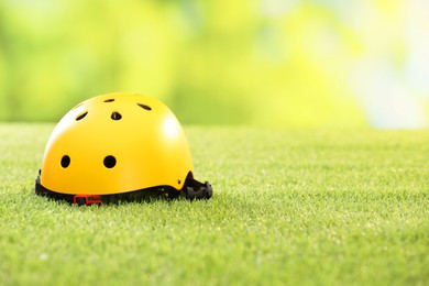 Yellow protective helmet on green grass, space for text