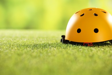 Yellow protective helmet on green grass, space for text