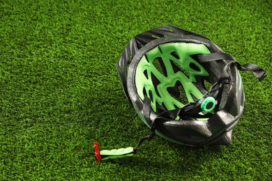 Stylish protective helmet on green grass, space for text