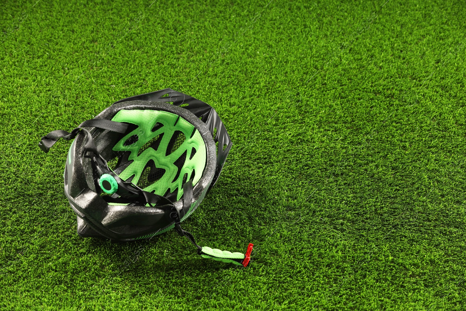 Photo of Stylish protective helmet on green grass, space for text