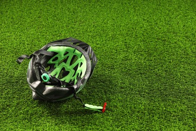 Photo of Stylish protective helmet on green grass, space for text