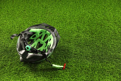 Stylish protective helmet on green grass, space for text