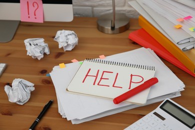 Photo of Notebook with word Help and stationery on wooden table at workplace