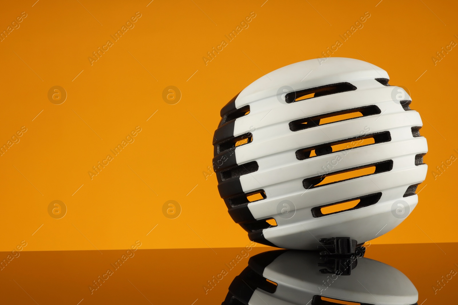 Photo of White protective helmet on mirror surface against orange background. Space for text