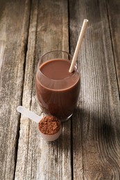 Photo of Delicious protein shake in glass and scoop with powder on wooden table