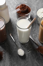 Photo of Delicious protein shakes in glasses, powder and spoons on grey table