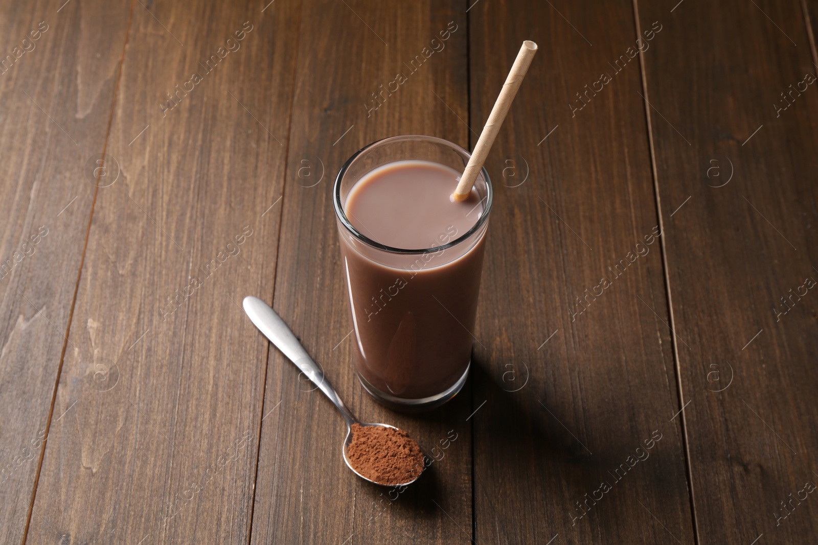 Photo of Delicious protein shake in glass and spoon with powder on wooden table