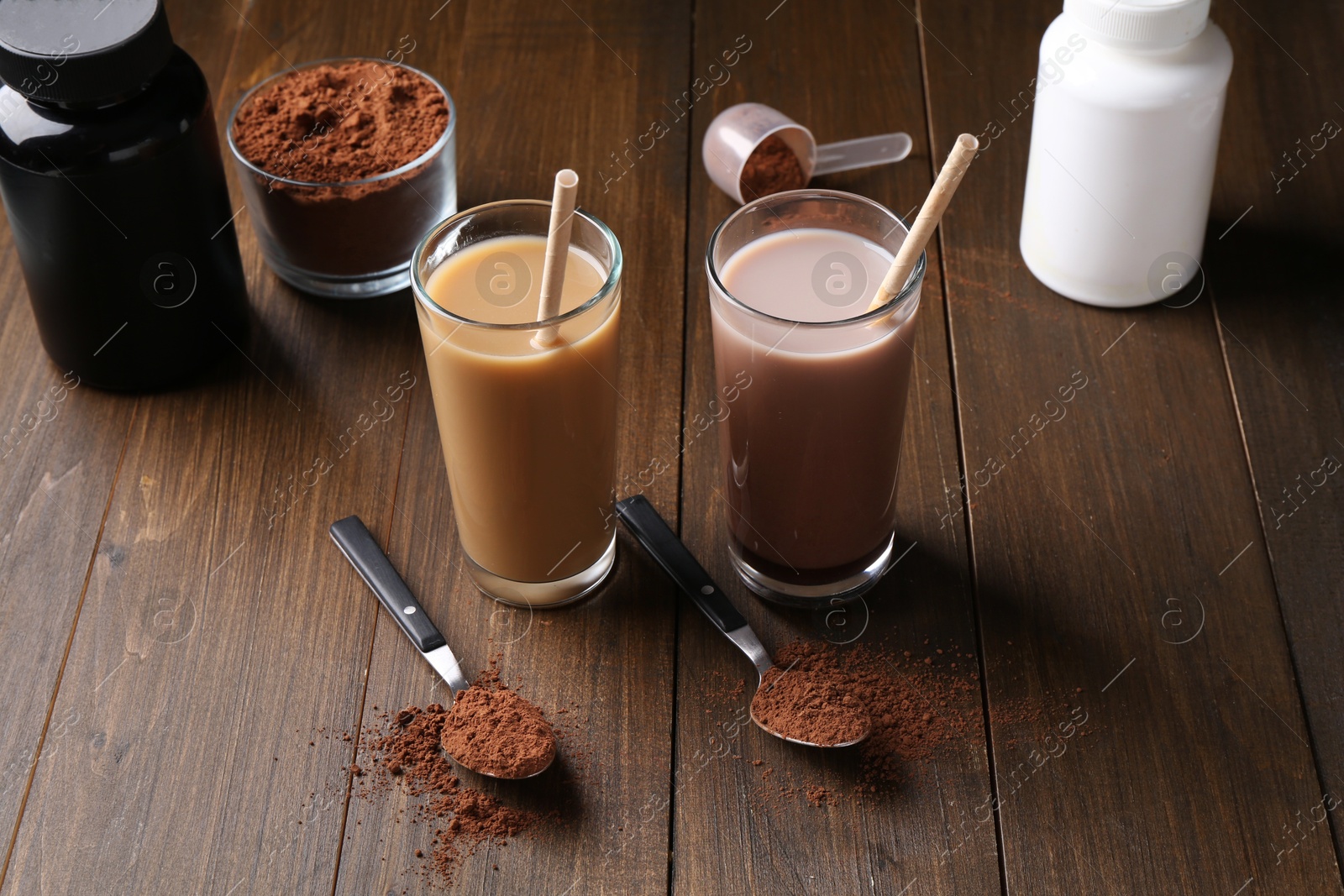 Photo of Delicious protein shakes in glasses, powder and spoons on wooden table